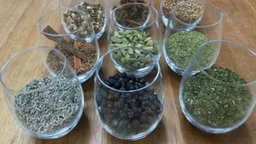 Nine glass containers filled with various spices.