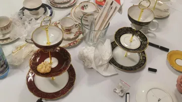 Verschiedene Teetassen und abgestufte Ständer auf dem Tisch.