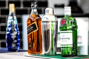 Bottles and cocktail shaker on bar.