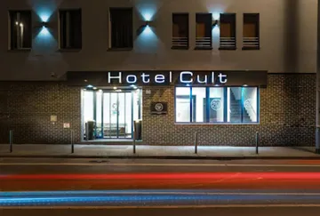 Hotel Cult entrance with neon lights at night.