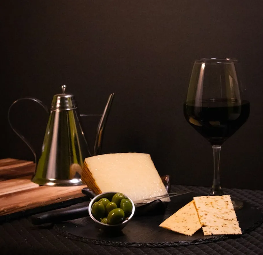 Käse, Oliven und Wein auf einem dunklen Tisch.