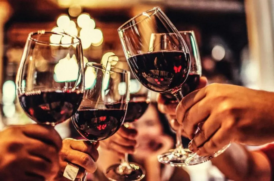 Hands clinking glasses of red wine in celebration.