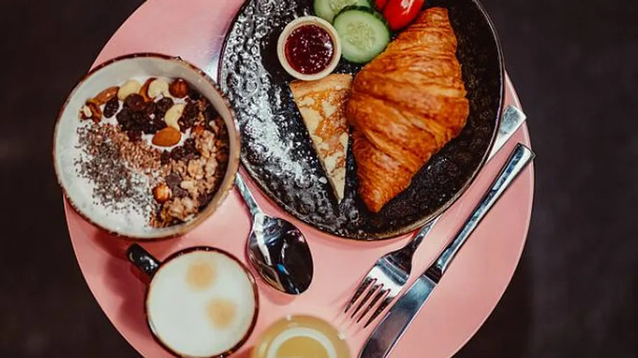 Frühstückstablett mit Croissant, Joghurtschale und Kaffee.