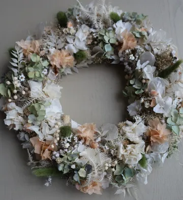Floral wreath with green and peach blooms.