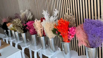 Colorful dried flowers in metal vases on stools.