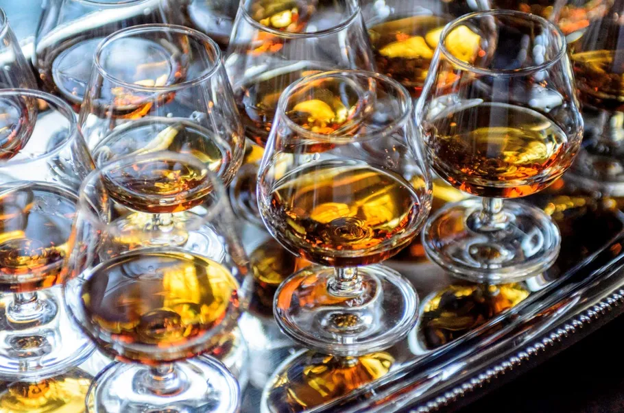Several glasses of cognac on a shiny tray.