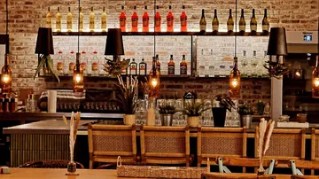 Modern bar with bottles and pendant lights.