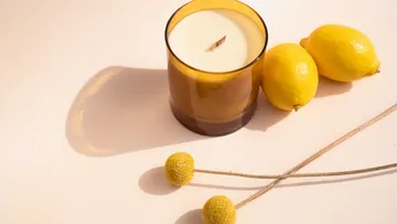 Kerze mit Zitronen und Blumen auf Tisch.