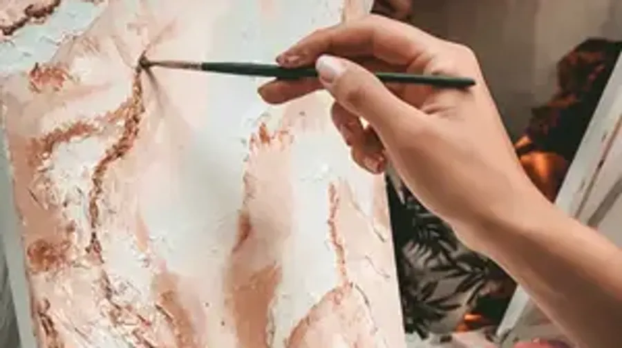 Person painting abstract design on canvas.