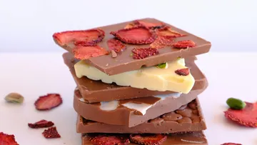 Gestapelte Schokoriegel mit getrockneten Erdbeeren darüber.