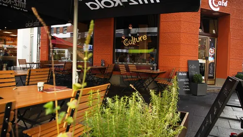 Outdoor café tables with orange facade background.