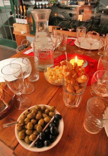Table with olives, cheese, breadsticks, and drinks.