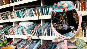 Fabric bolts on shelves with a mirror.