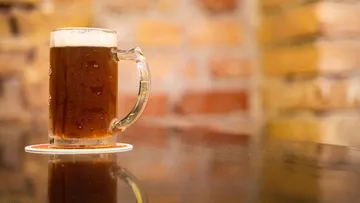 Beer mug on table with brick wall background.