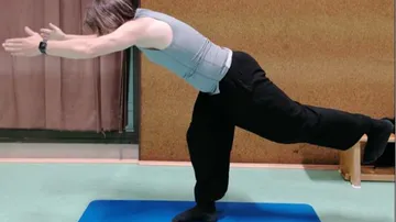 Person balancing on yoga mat in warrior pose.