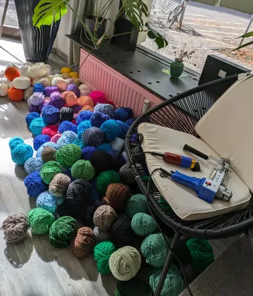Bunte Wollknäuel in der Nähe eines Stuhls drinnen.