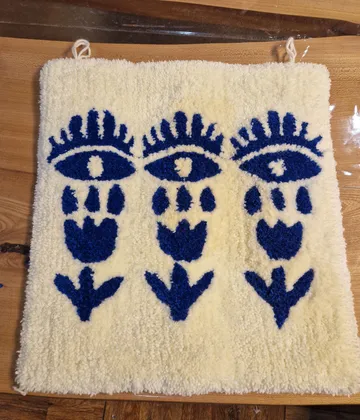 Handgefertigter Teppich mit blauen Augenmustern.