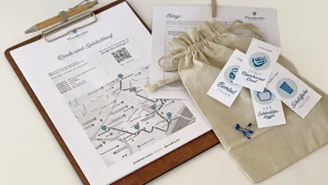 Clipboard with map, paper, and pouch on table.