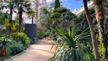 Pathway through lush garden with people walking.