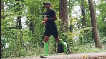 Person jogging on forest trail, wearing green socks.