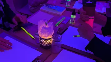 Leute, die unter UV-Licht mit leuchtenden Gegenständen basteln.