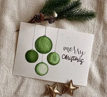 Handgefertigte Weihnachtskarte mit grünen Ornamenten.