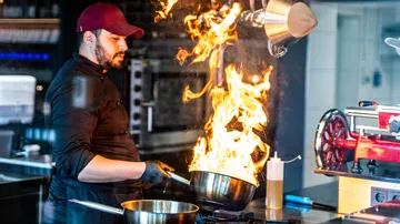 Chef flambiert eine Schale in einer gewerblichen Küche.