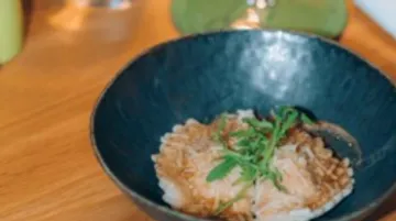 Rice dish in black bowl on table.