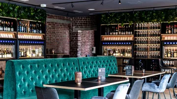 Schickes Barinterieur mit grünen Sofas und Weinregalen.