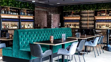 Moderne Weinbar mit grünen Sitzgelegenheiten und Weinauslagen.