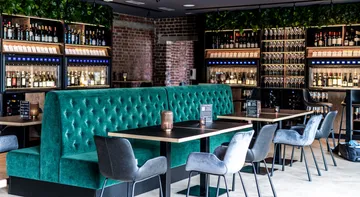 Schicke Restaurant-Lounge mit Sitzgelegenheiten aus Samt und Weinauslage.