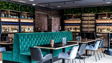 Moderne Weinbar mit grünen Ständen und Weinauslagen.