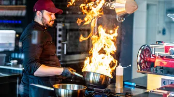 Chef cooking with large flames in kitchen