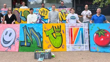 Gruppe, die draußen farbenfrohe Graffiti-Kunstleinwände hält.