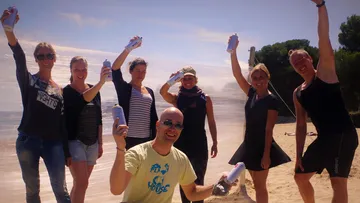 Group holding spray cans on a beach.