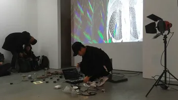 Person setting up electronic equipment in gallery.