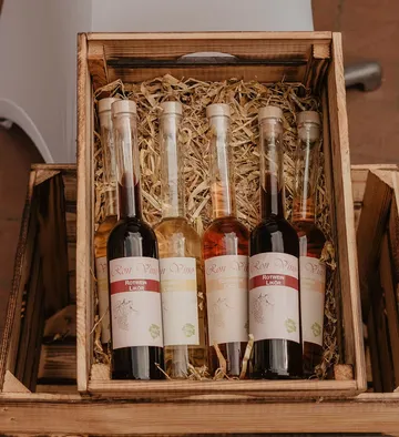 Five wine bottles in wooden crate with straw.