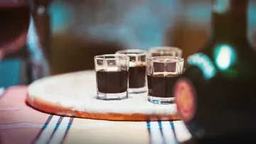 Drei Schnapsgläser mit dunkler Flüssigkeit auf dem Tisch