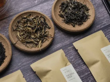 Tea leaves lie on bowls, with tea bags packed next to them.