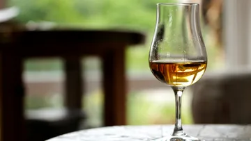 Whiskyglas auf einem Tisch, verschwommener Hintergrund.