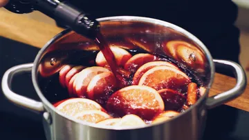Wine being poured into pot with oranges.