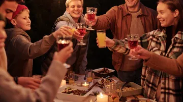 Gruppe von Leuten, die Getränke beim Abendessen anrösten.