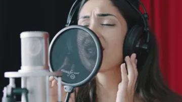 Person, die im Studio ins Mikrofon singt.