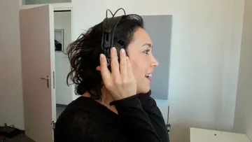 Person, die Kopfhörer trägt und in einem Zimmer lächelt.