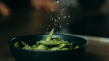 Edamame in schwarzer Schüssel mit Salzstreuung
