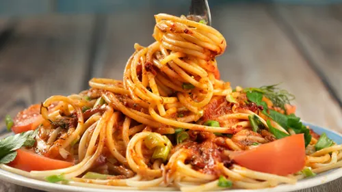 Fork twirling spaghetti with tomato sauce.