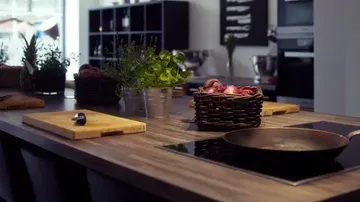 Modern kitchen with herbs and skillet on counter.