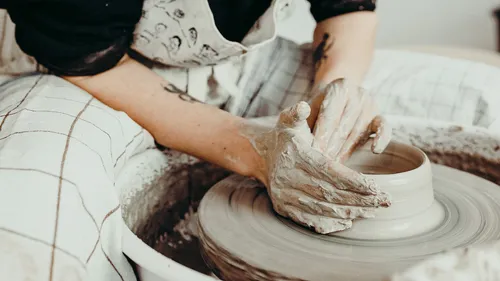 Person shaping clay on pottery wheel.