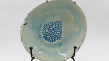 Keramikschale mit ausgestelltem filigranem blauem Muster.