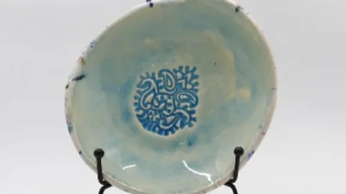 Keramikschale mit ausgestelltem filigranem blauem Muster.